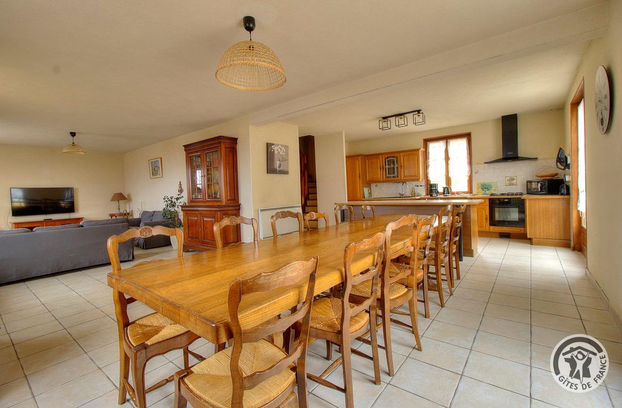 Grande table en bois pour la salle à manger, avec la cuisine équipée au fond