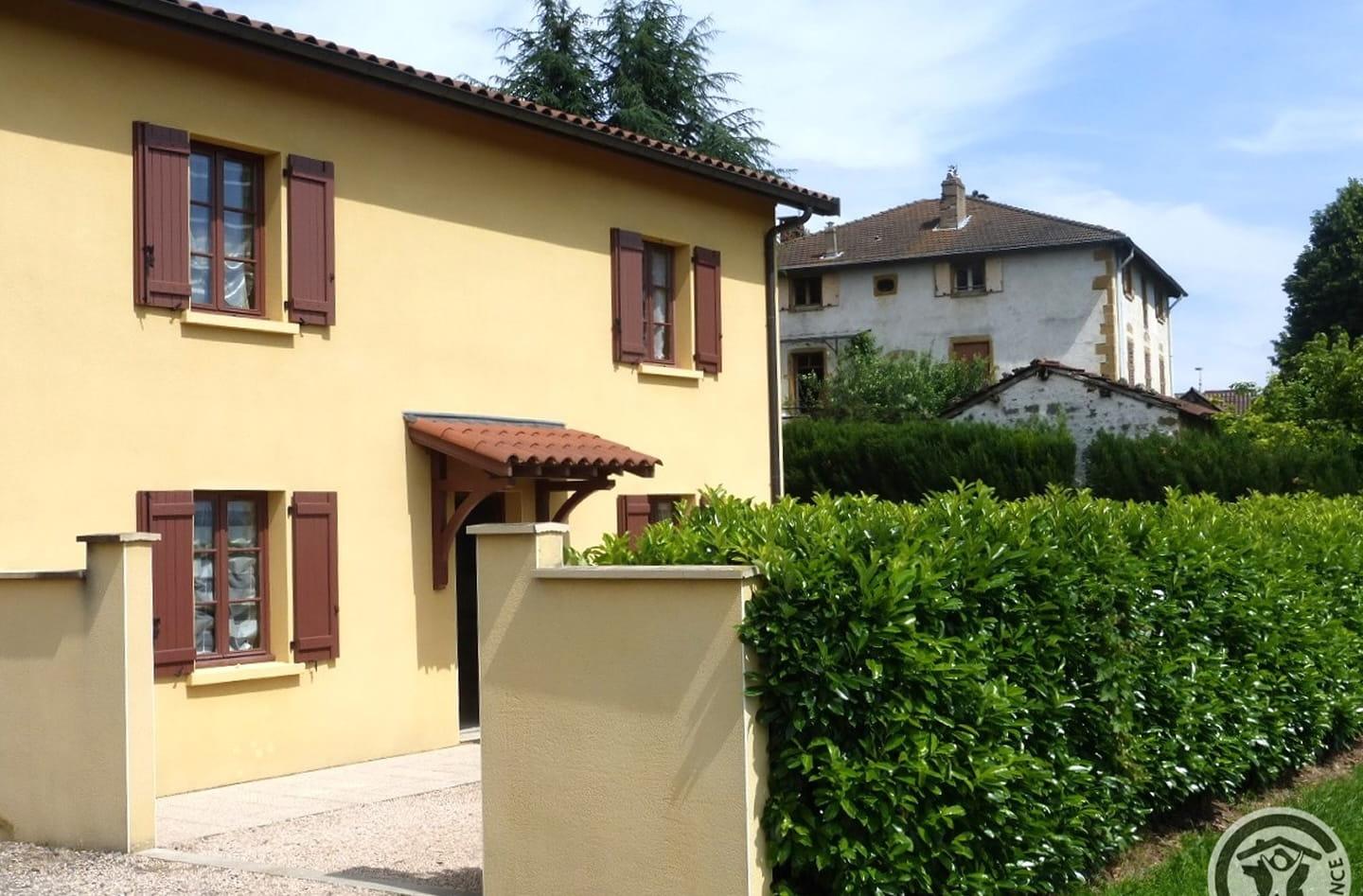 Façade jaune du gîte Plein Soleil, volets bruns et petit auvent de tuiles
